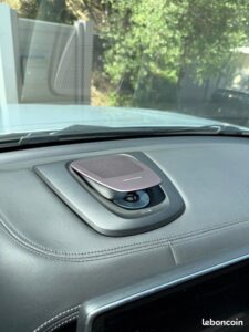 Intérieur voiture avec tableau de bord en cuir foncé et haut-parleur Bang & Olufsen rétractable. Vue sur le pare-brise.