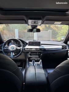 Intérieur BMW X5/X6 moderne, vue depuis l'arrière. Volant sport, tableau de bord numérique, levier de vitesse. Toit panoramique. 'leboncoin'.