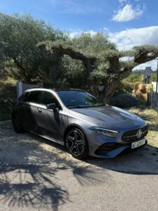 Mercedes-Benz Classe A grise garée sous un vieil olivier, avec toit ouvrant panoramique et jantes noires. Plaque A7 CONCEPT.