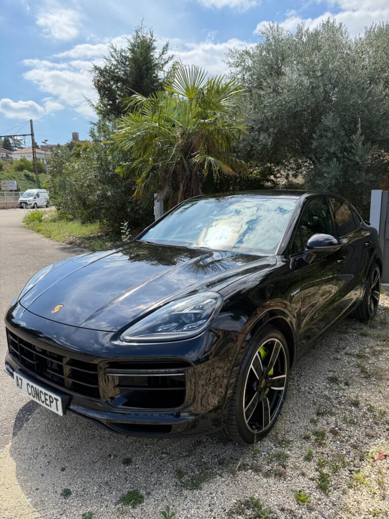 Porsche Cayenne Coupé e-hybrid noir brillant garé en extérieur ensoleillé. Jantes sportives vertes. Plaque d'immatriculation 'AZ CONCEPT'.