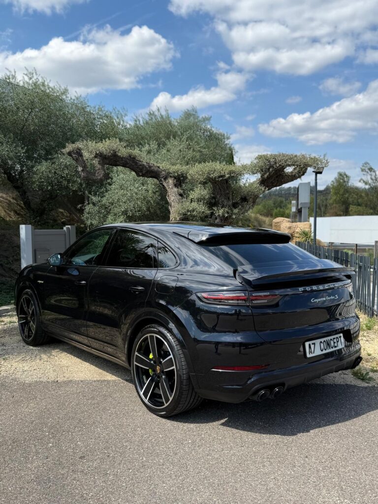 Porsche Cayenne Turbo S hybride noire, plaque 'A7 CONCEPT', garée en extérieur. Jantes bicolores, étriers de frein jaunes, sous ciel bleu avec arbres.